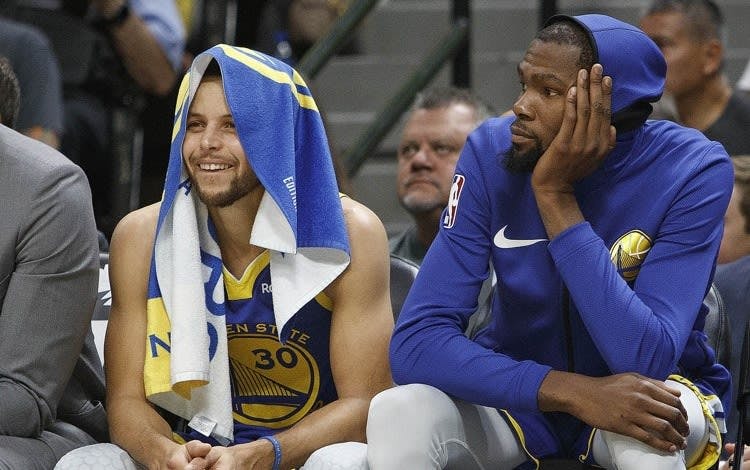 Stephen Curry and Kevin Durant look on from the bench