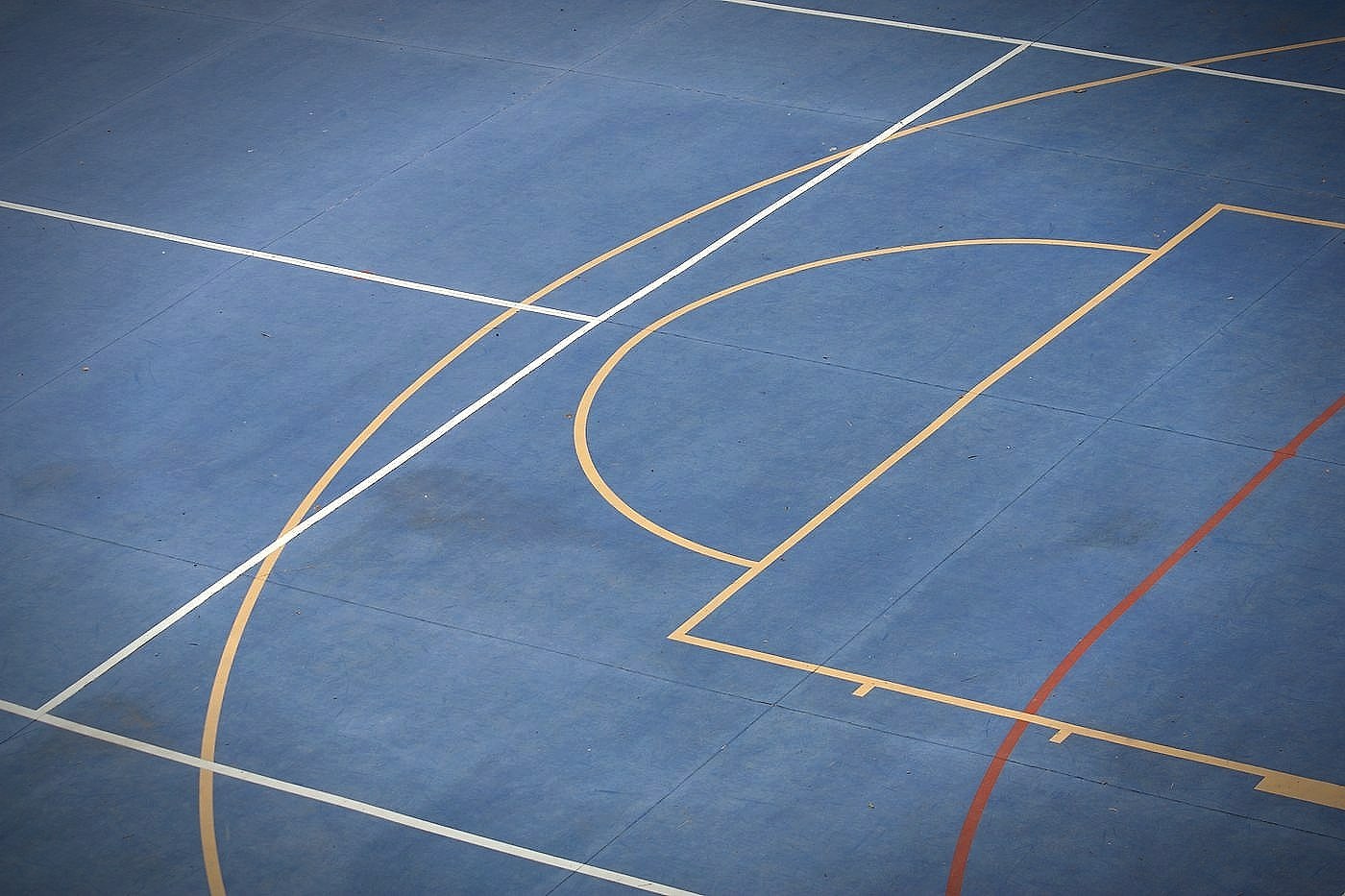 Painted arc and lane lines on a blue basketball court seen from above