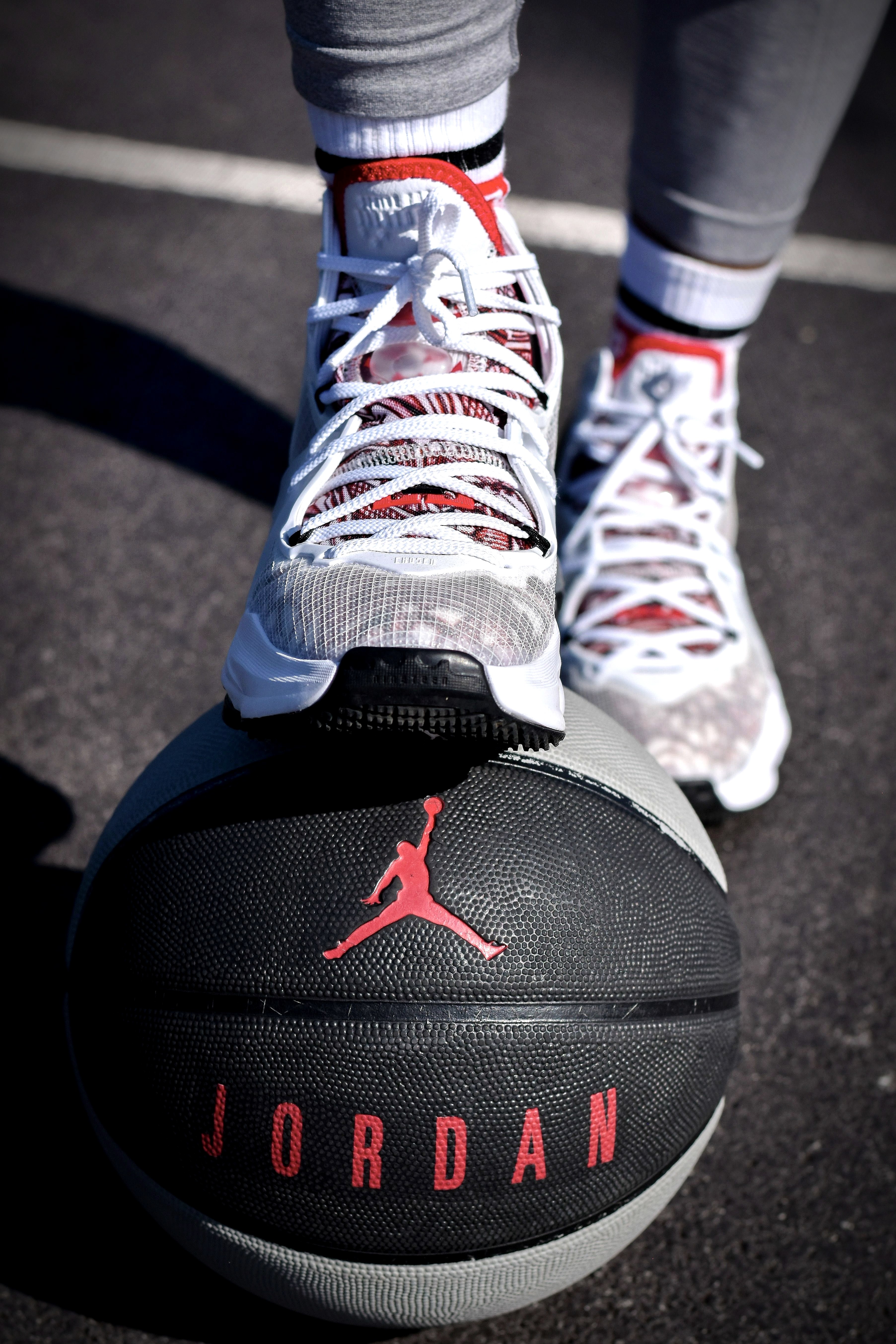 White Air Jordan sneakers resting on a basketball on an outdoor court