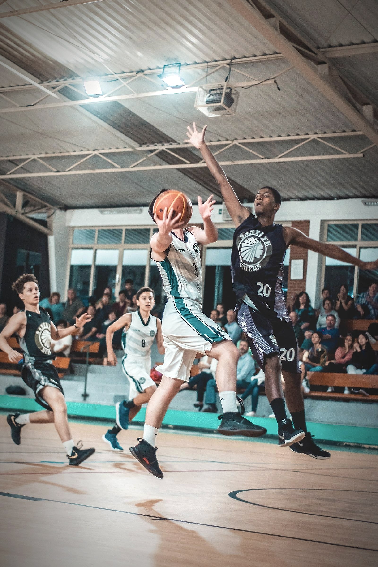 Basketball players in motion during a game, one player driving past a defender