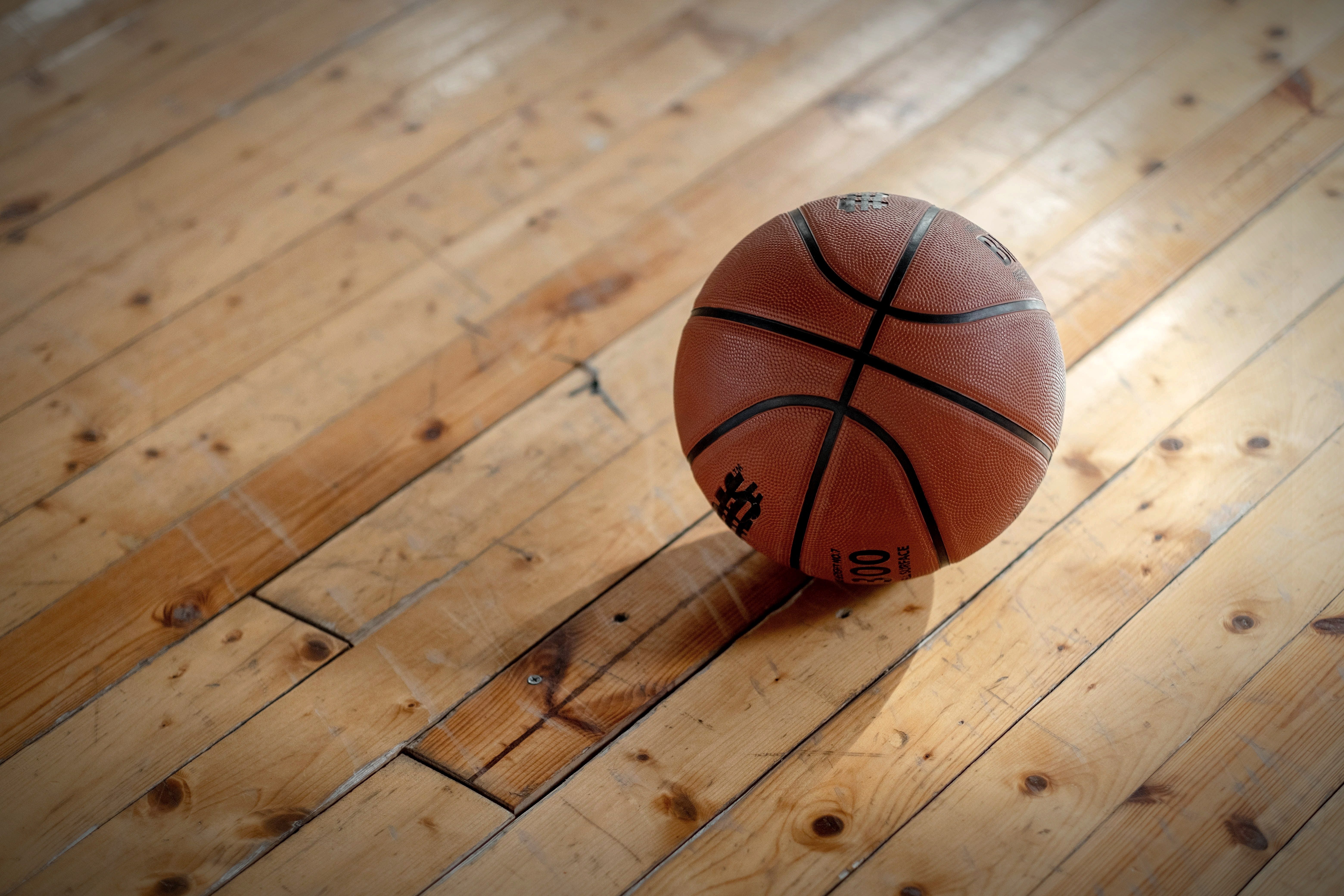 A basketball resting on a polished hardwood gym floor